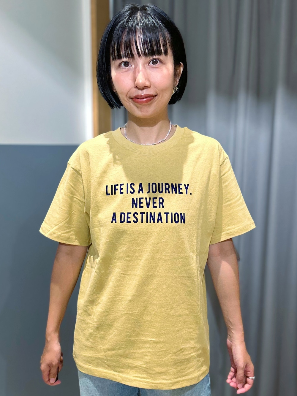 ブラウン系のベスト、ブルー系のデニムパンツ、ベージュ系のトートバッグを着用したレディースの夏コーディネートの6枚目の写真