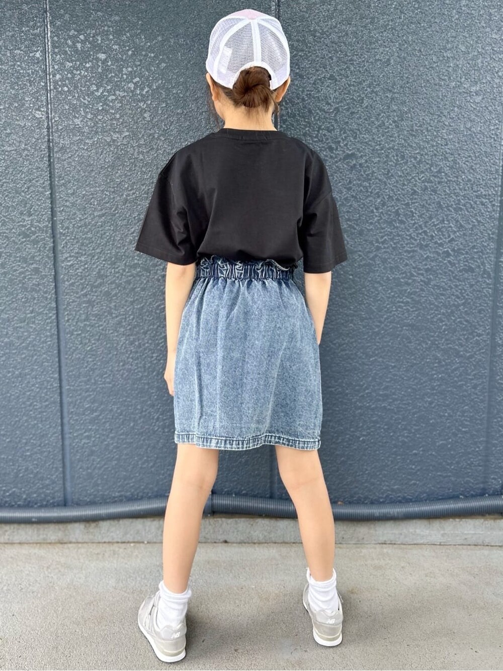 ブラック系のTシャツ/カットソー、ブルー系のデニムスカート、パープル系のキャップを着用したレディースの春コーディネートの3枚目の写真