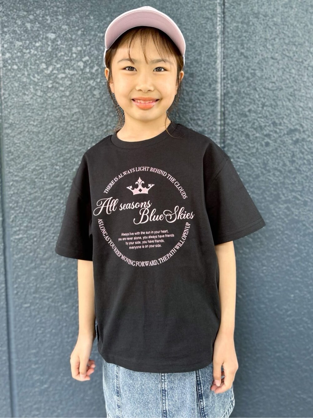 ブラック系のTシャツ/カットソー、ブルー系のデニムスカート、パープル系のキャップを着用したレディースの春コーディネートの4枚目の写真