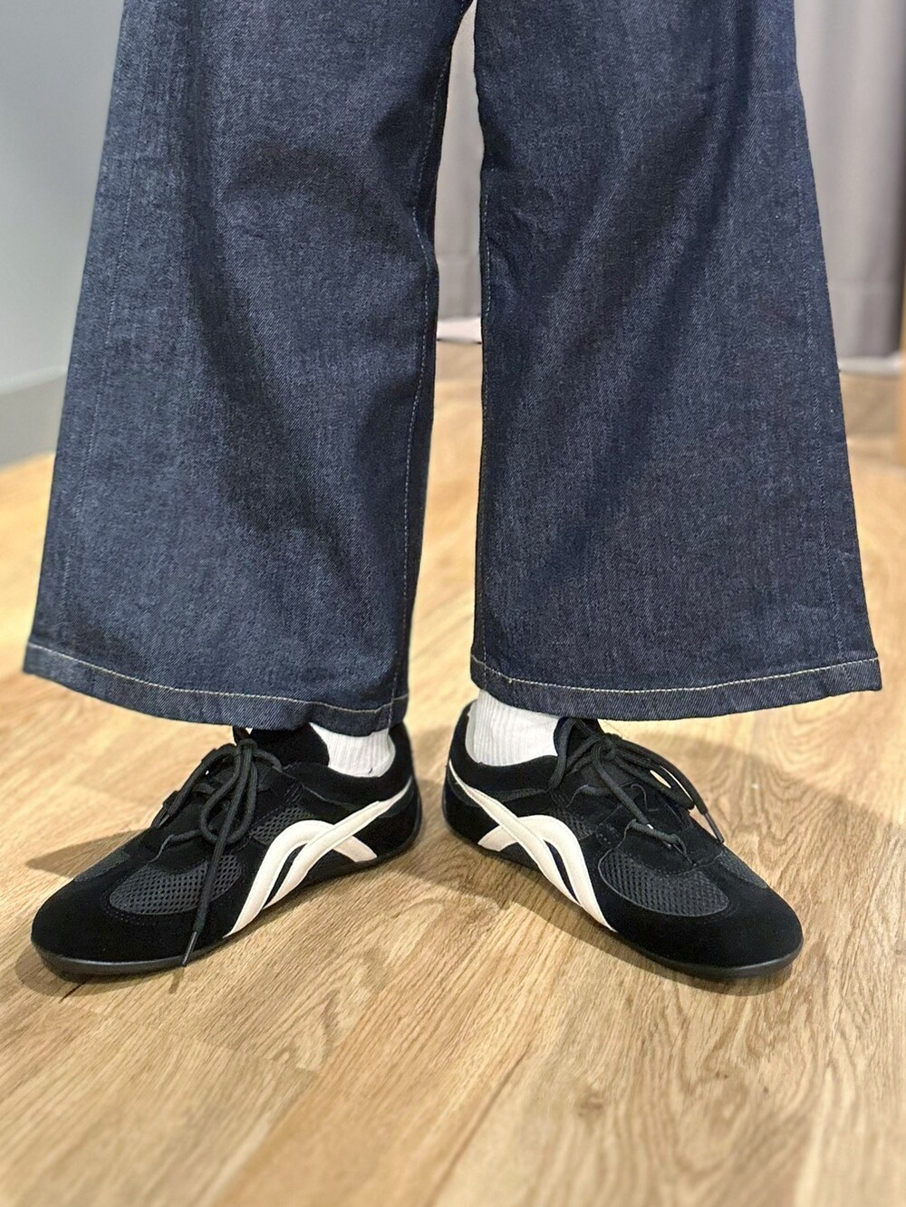 レッド系のニット/セーター、ブラック系のタンクトップ、ブルー系のデニムパンツを着用したレディースの秋コーディネートの9枚目の写真