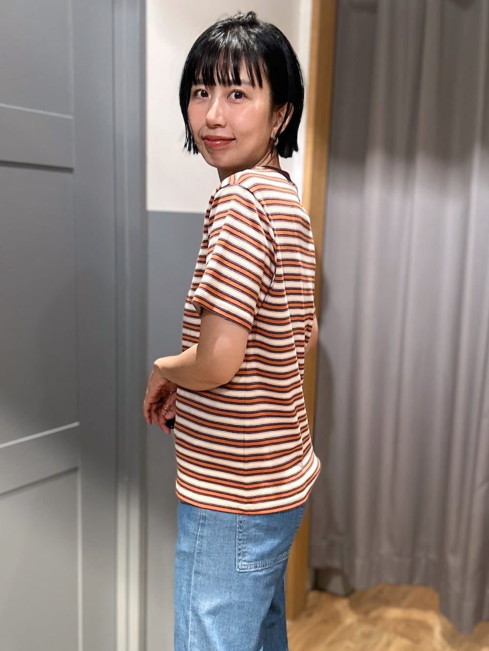 オレンジ系のTシャツ/カットソー、ブラウン系のテーラードジャケット、ブルー系のデニムパンツを着用したレディースの夏コーディネートの7枚目の写真
