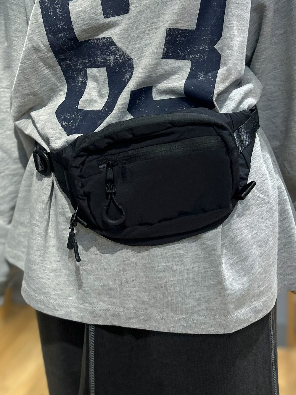 グレー系のTシャツ/カットソー、グレー系のスカート、ブラック系のボディバッグ/ウエストポーチを着用したレディースの秋コーディネートの8枚目の写真