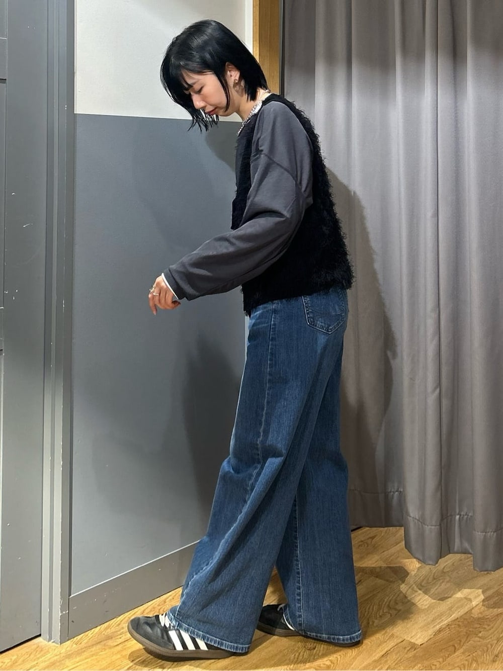 グレー系のTシャツ/カットソー、ブラック系のベスト、ブルー系のデニムパンツを着用したレディースの春コーディネートの4枚目の写真