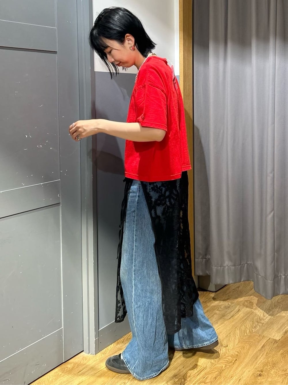 レッド系のTシャツ/カットソー、ブラック系のスカート、ブラック系のショルダーバッグを着用したレディースの春コーディネートの3枚目の写真