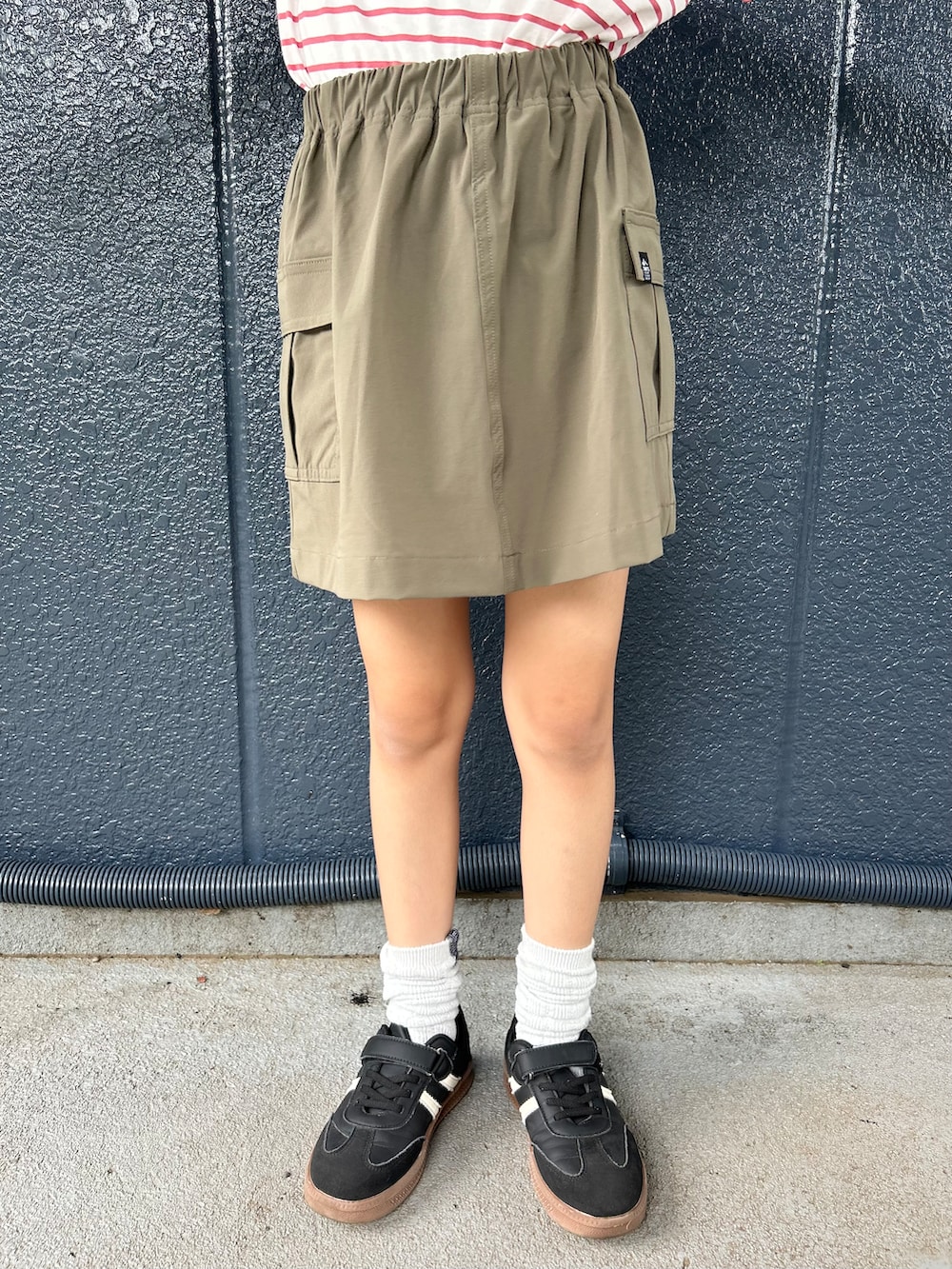 レッド系のTシャツ/カットソー、ブラウン系のスカート、ベージュ系のキャップを着用したキッズの夏コーディネートの4枚目の写真