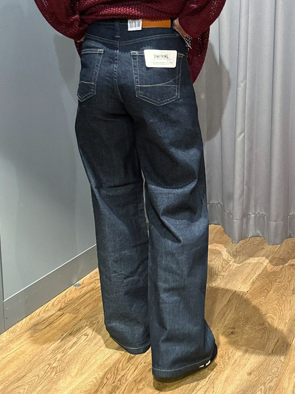 レッド系のニット/セーター、ブラック系のタンクトップ、ブルー系のデニムパンツを着用したレディースの秋コーディネートの8枚目の写真