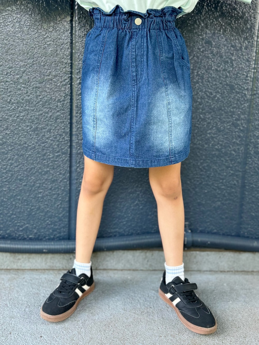 グリーン系のTシャツ/カットソー、ブルー系のデニムスカート、ブラック系のキャップを着用したキッズの夏コーディネートの7枚目の写真