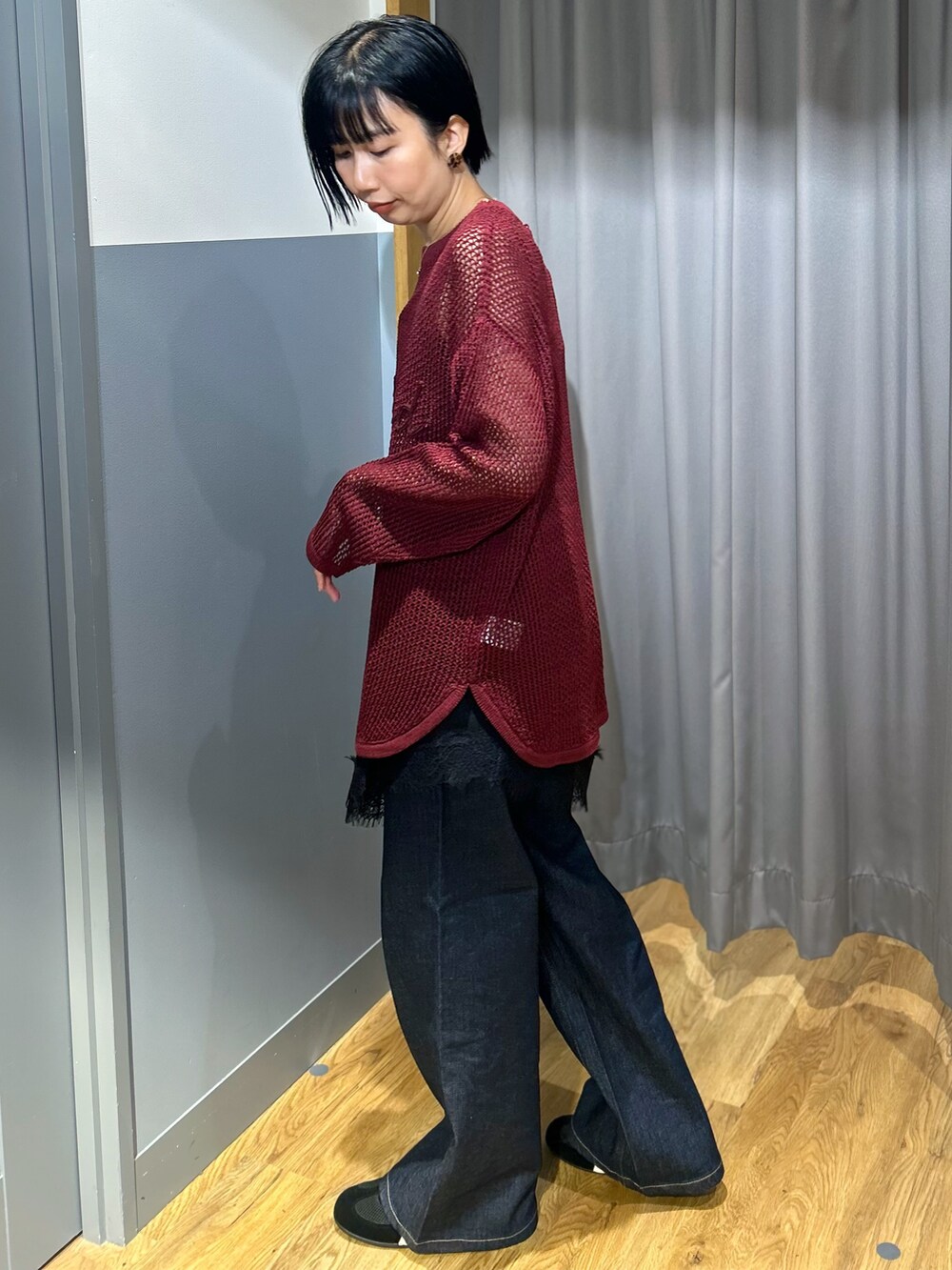 レッド系のニット/セーター、ブラック系のタンクトップ、ブルー系のデニムパンツを着用したレディースの秋コーディネートの2枚目の写真