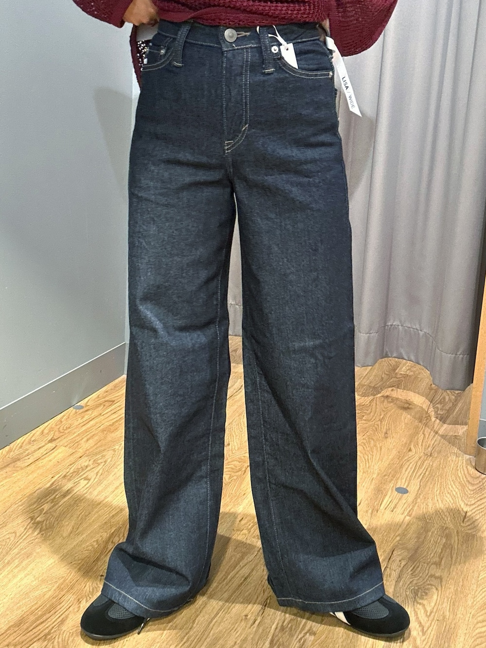 レッド系のニット/セーター、ブラック系のタンクトップ、ブルー系のデニムパンツを着用したレディースの秋コーディネートの7枚目の写真