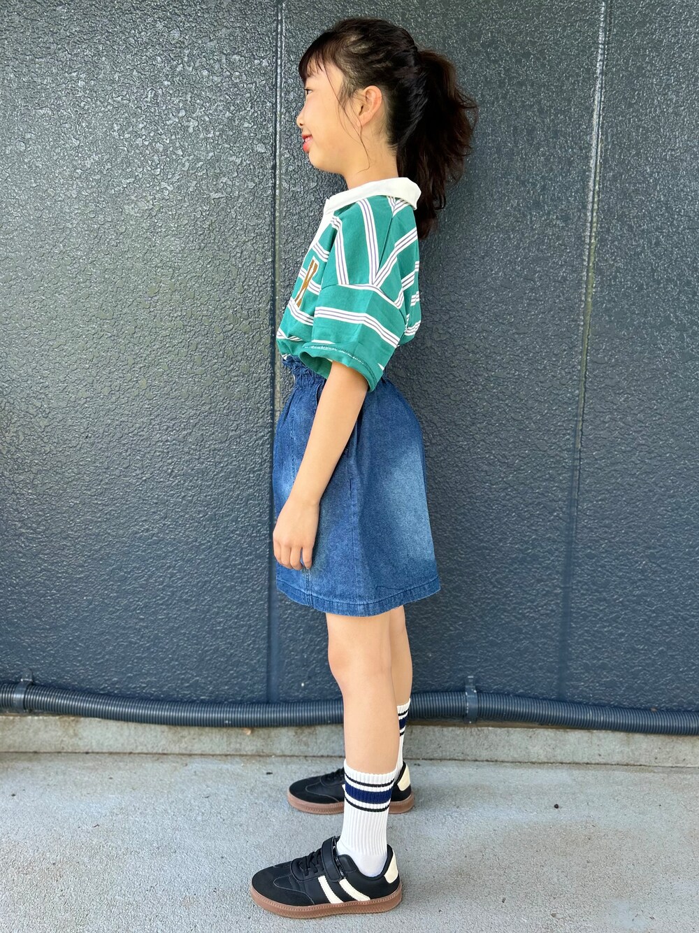 グリーン系のTシャツ/カットソー、ブルー系のデニムスカート、ブラック系のショルダーバッグを着用したキッズの春コーディネートの3枚目の写真