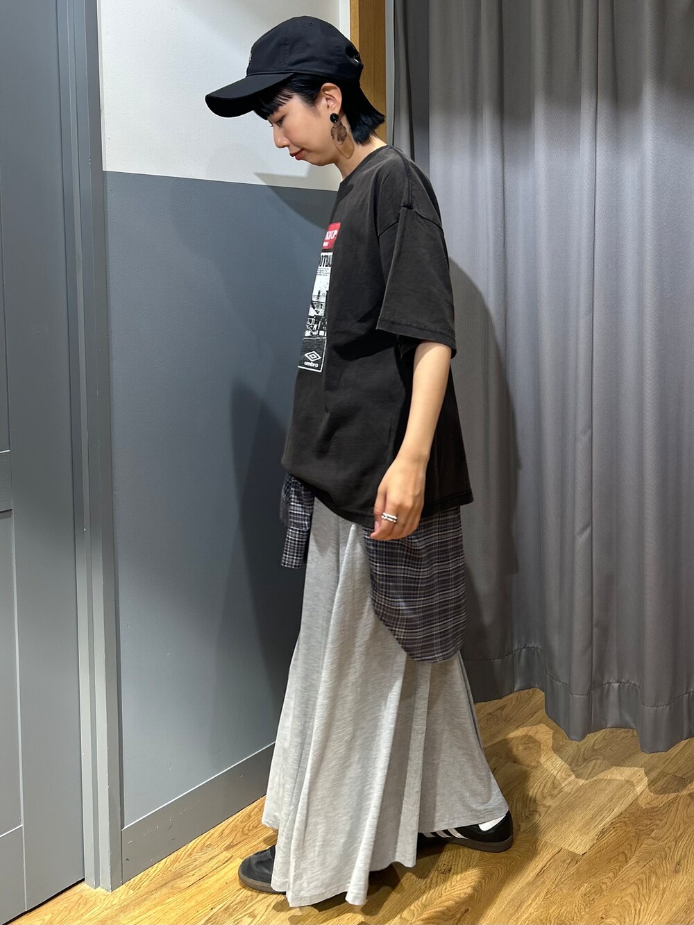 グレー系のスカート、グレー系のシャツ/ブラウス、ブラック系のキャップを着用したレディースの夏コーディネートの2枚目の写真