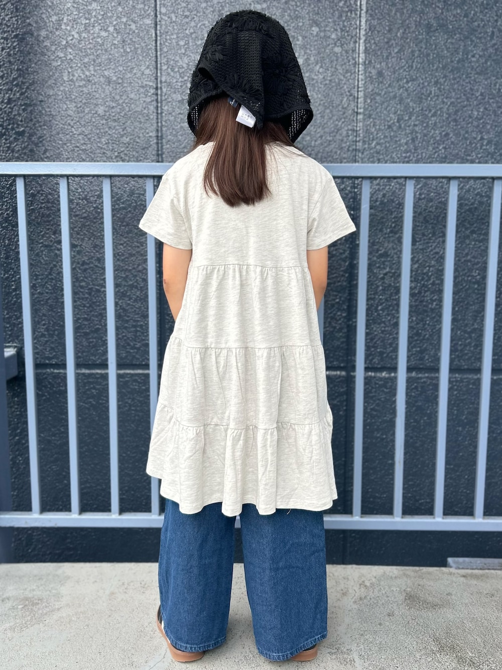 ブルー系のデニムパンツ、ホワイト系のルームワンピース、ブラック系のバンダナ/スカーフを着用したキッズの夏コーディネートの3枚目の写真