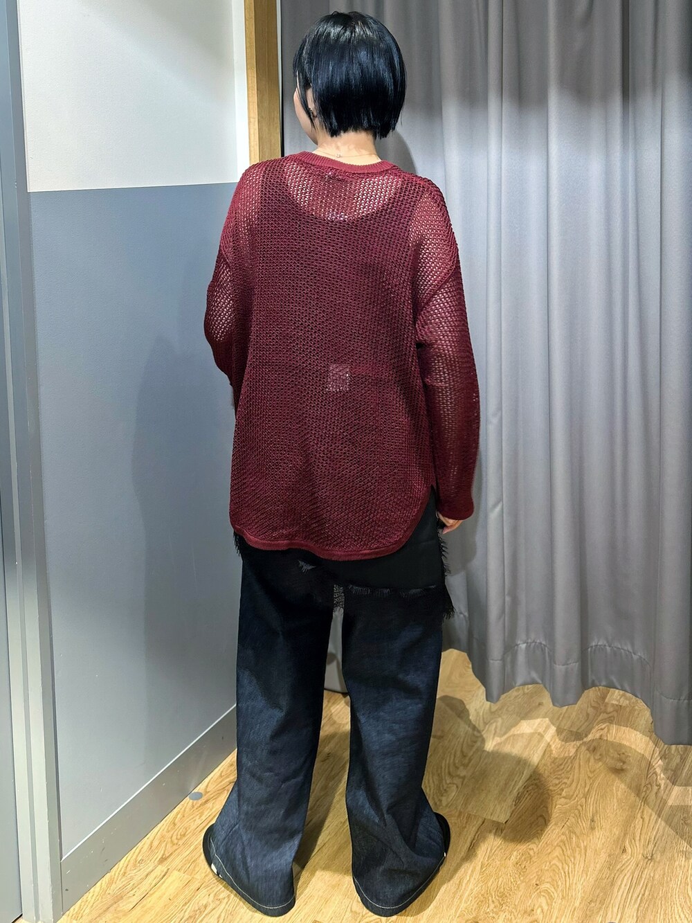 レッド系のニット/セーター、ブラック系のタンクトップ、ブルー系のデニムパンツを着用したレディースの秋コーディネートの3枚目の写真