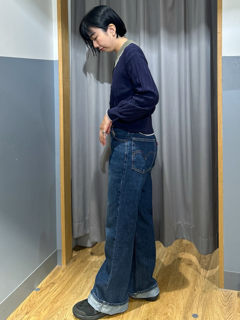 ブルー系のニット/セーター、ブルー系のデニムパンツ、グリーン系のショルダーバッグを着用したレディースの秋コーディネートの2枚目の写真