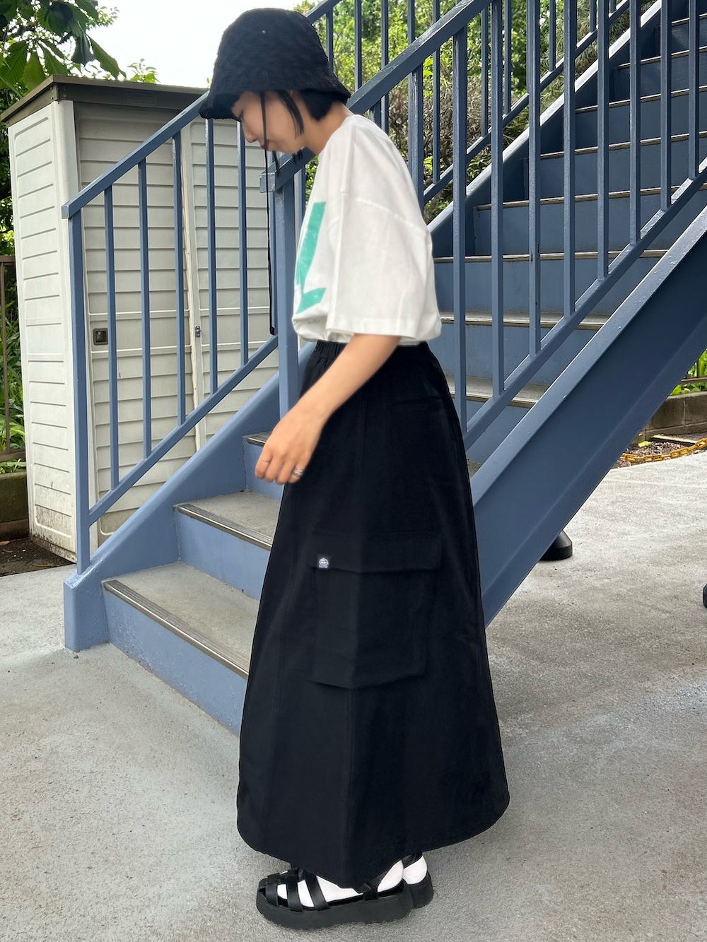 ホワイト系のTシャツ/カットソー、ブラック系のスカート、ブラック系のハットを着用したレディースの春コーディネートの3枚目の写真