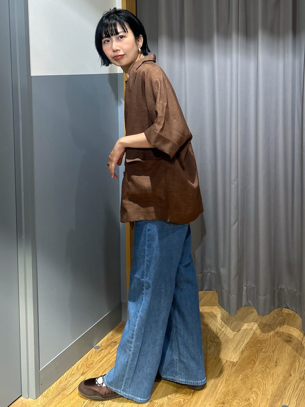 オレンジ系のTシャツ/カットソー、ブラウン系のテーラードジャケット、ブルー系のデニムパンツを着用したレディースの夏コーディネートの3枚目の写真