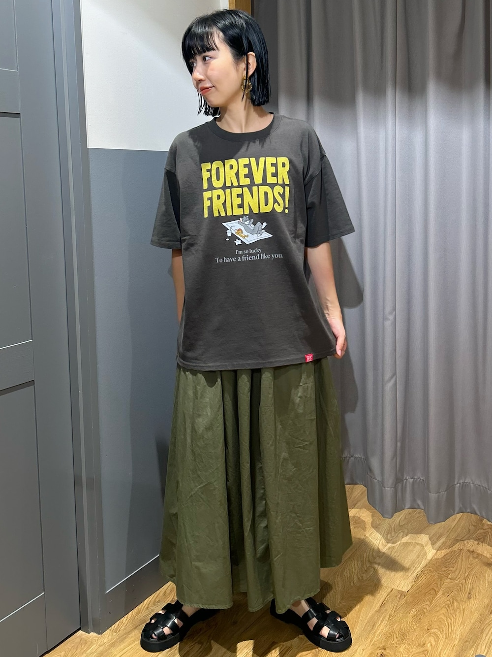 グレー系のTシャツ/カットソー、グリーン系のスカート、ブラック系のショルダーバッグを着用したレディースの夏コーディネートの2枚目の写真