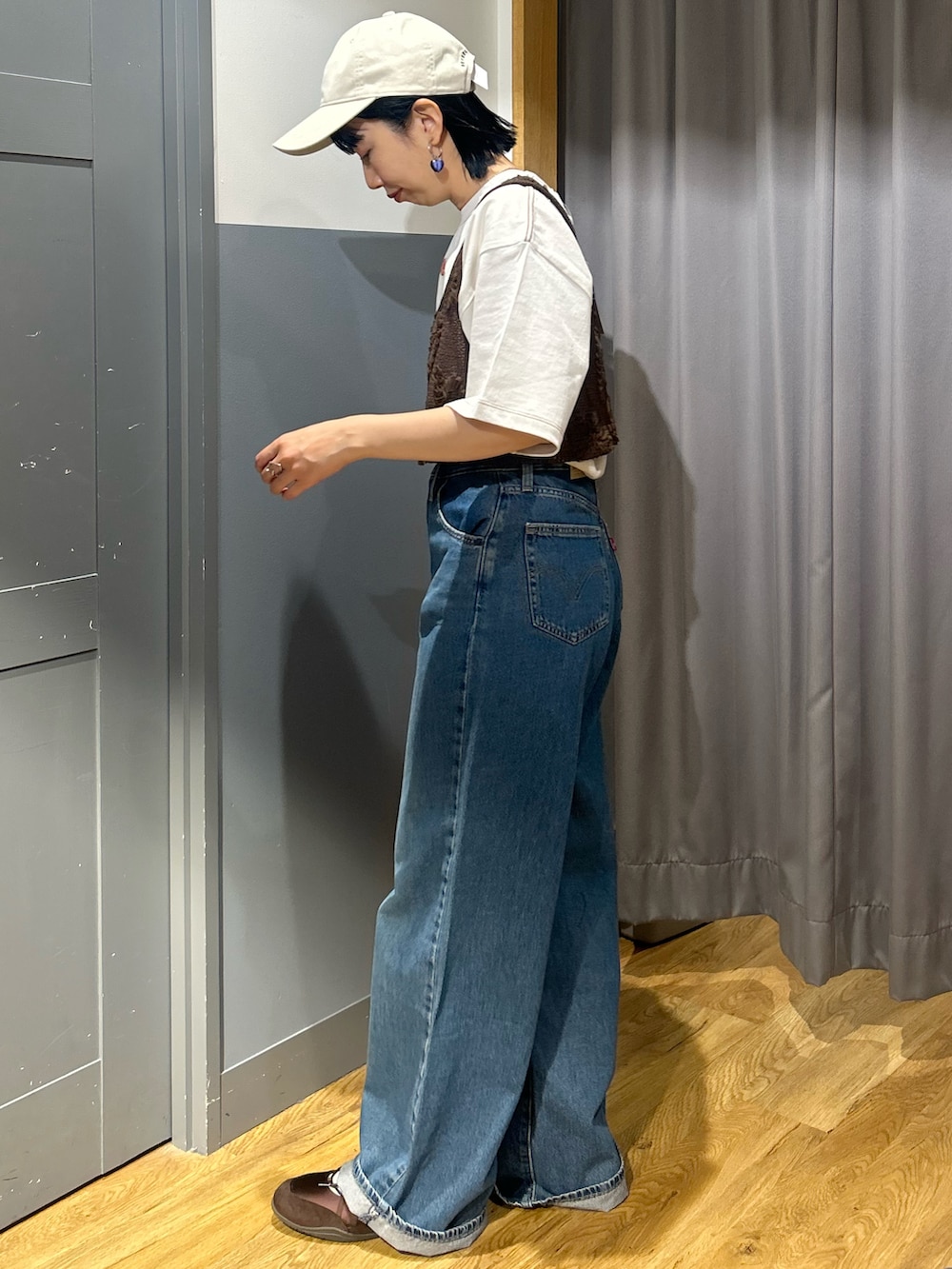 ホワイト系のTシャツ/カットソー、ブルー系のデニムパンツ、ブラウン系のベストを着用したレディースの春コーディネートの2枚目の写真