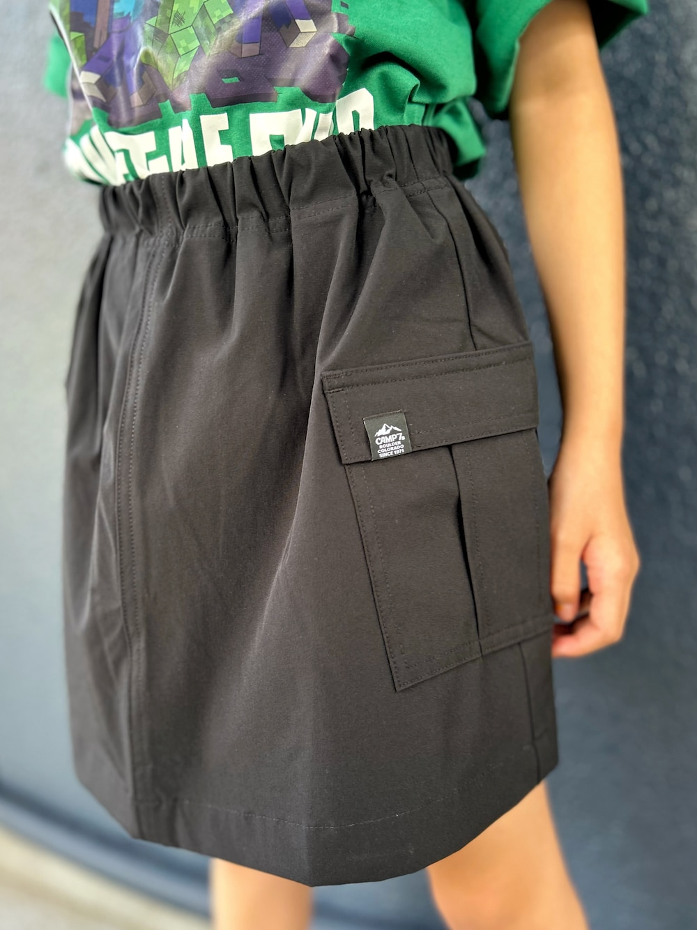 グリーン系のTシャツ/カットソー、ブラック系のスカート、ブラック系のハットを着用したキッズの夏コーディネートの7枚目の写真