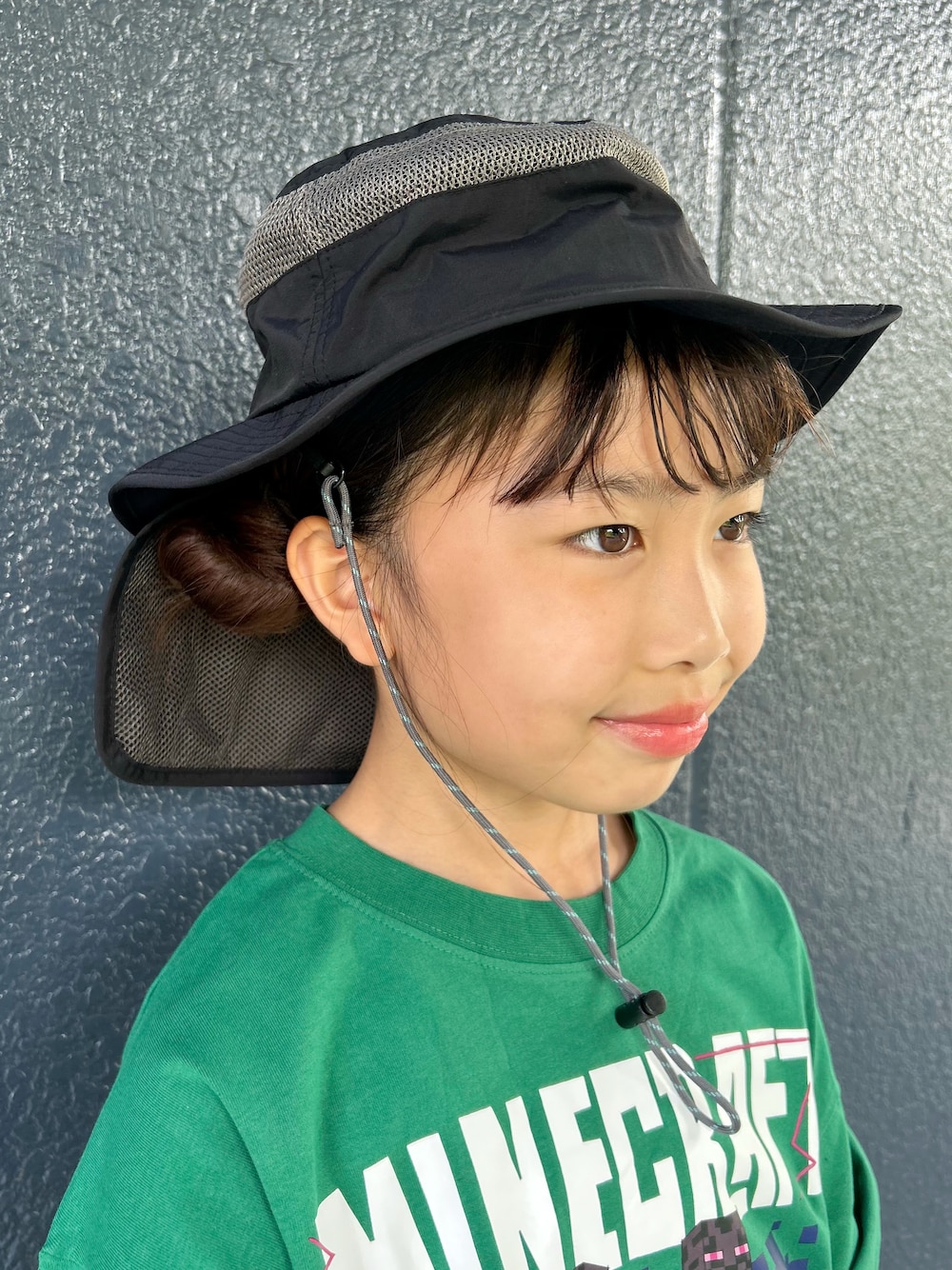 グリーン系のTシャツ/カットソー、ブラック系のスカート、ブラック系のハットを着用したキッズの夏コーディネートの9枚目の写真