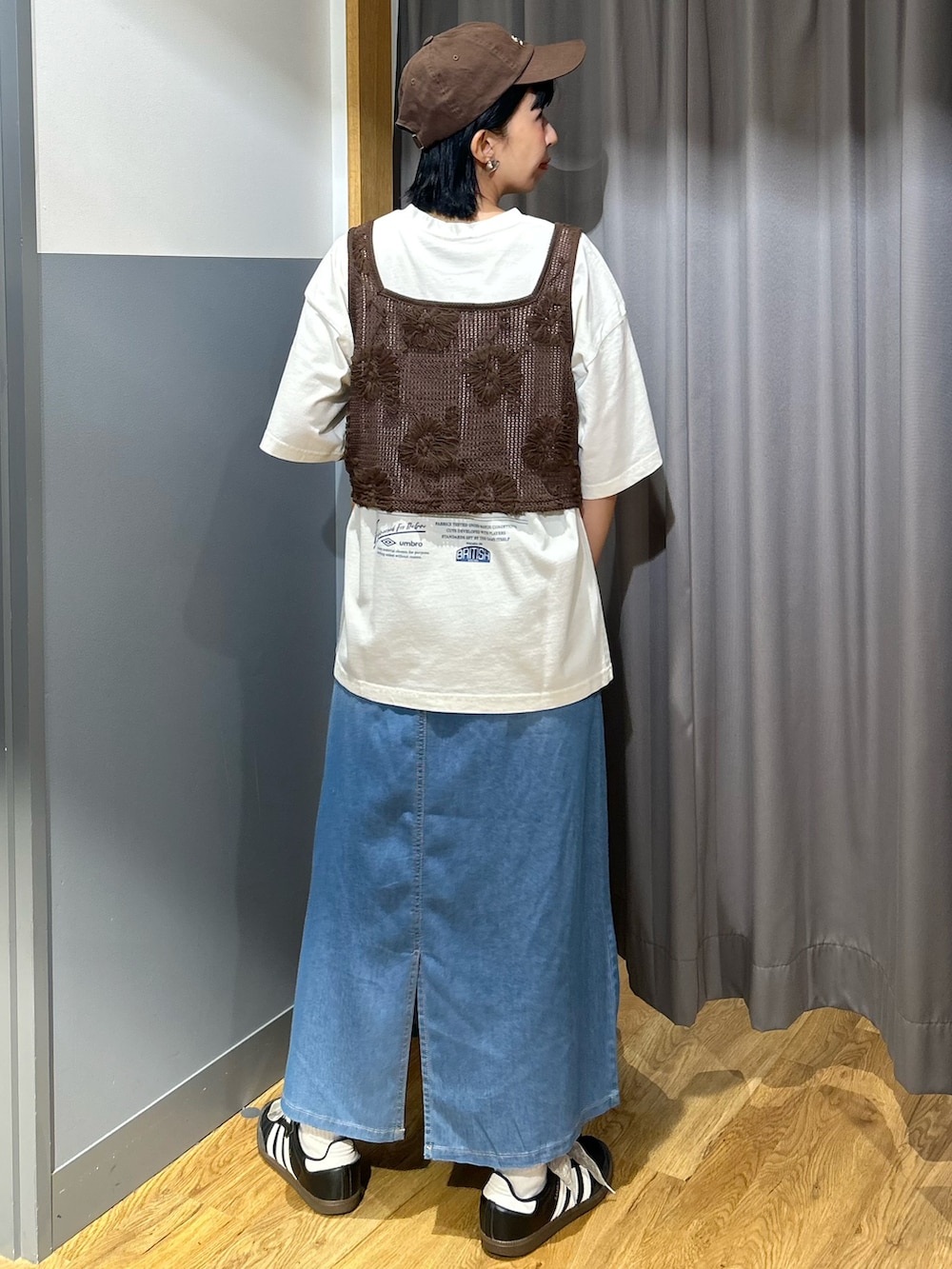 ブラウン系のベスト、ブルー系のスカート、ブラウン系のキャップを着用したレディースの夏コーディネートの3枚目の写真