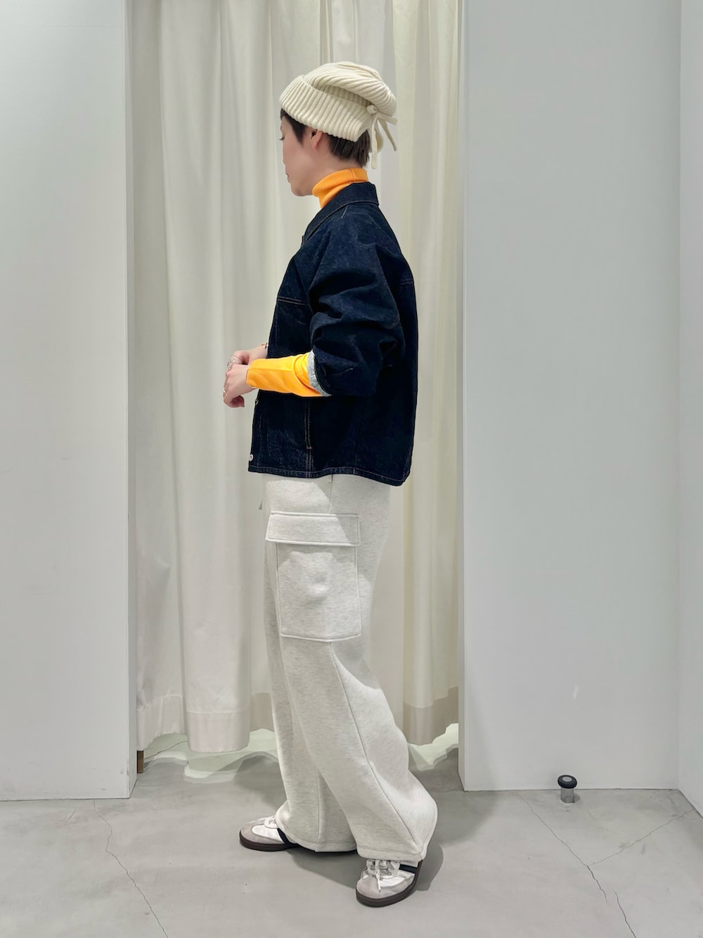 オレンジ系のニット/セーター、ブルー系のデニムジャケットを着用したレディースの冬コーディネートの2枚目の写真