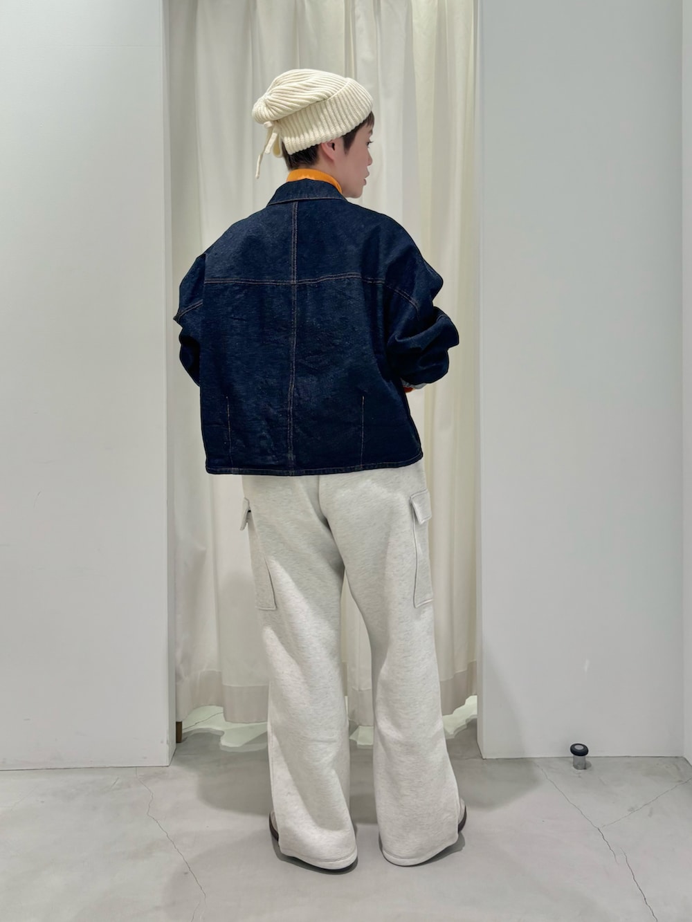 オレンジ系のニット/セーター、ブルー系のデニムジャケットを着用したレディースの冬コーディネートの3枚目の写真