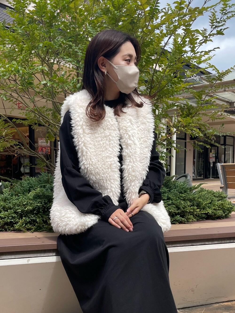 ホワイト系のベスト、ブラック系のワンピース/ドレス、ブラック系のブーツを着用したレディースの秋コーディネートの2枚目の写真