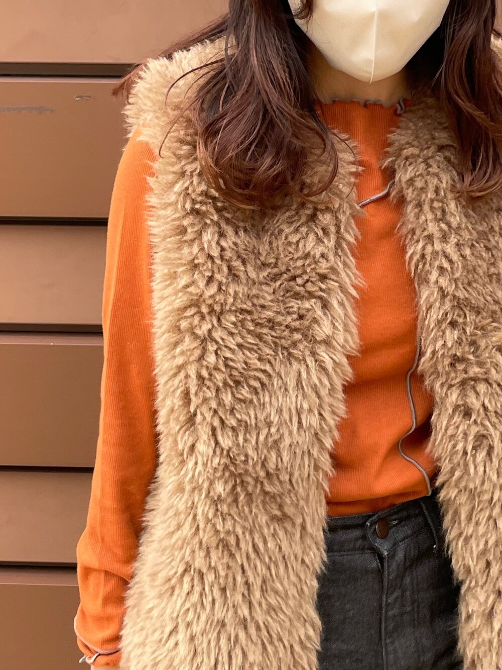 ホワイト系のベスト、オレンジ系のTシャツ/カットソー、ブラック系のデニムパンツを着用したレディースの秋コーディネートの2枚目の写真