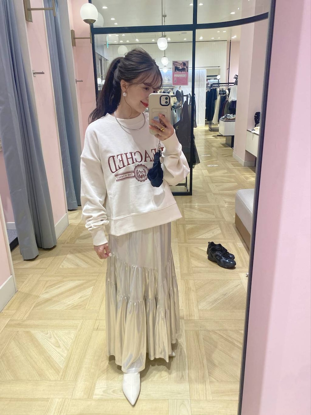 ホワイト系のスウェット、シルバー系のボストンバッグ、ホワイト系のブーツを着用したレディースの秋コーディネートの2枚目の写真