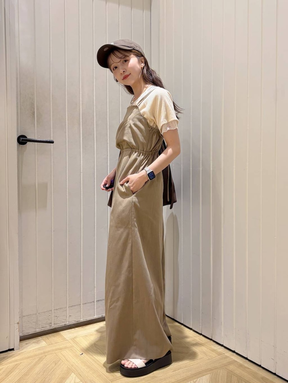 ブラウン系のショルダーバッグ、ホワイト系のサンダル、ホワイト系のTシャツ/カットソーを着用したレディースの春コーディネートの2枚目の写真
