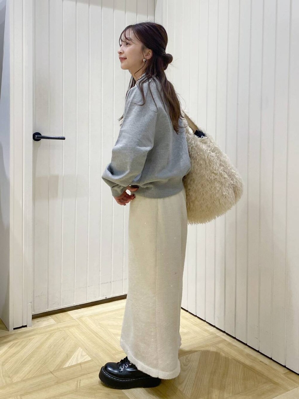 ホワイト系のトートバッグ、グレー系のスウェット、ゴールド系のネックレスを着用したレディースの冬コーディネートの2枚目の写真