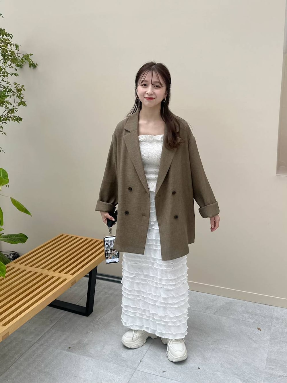 ホワイト系のスカート、ホワイト系のスニーカー、ブラウン系のテーラードジャケットを着用したレディースの冬コーディネートの3枚目の写真