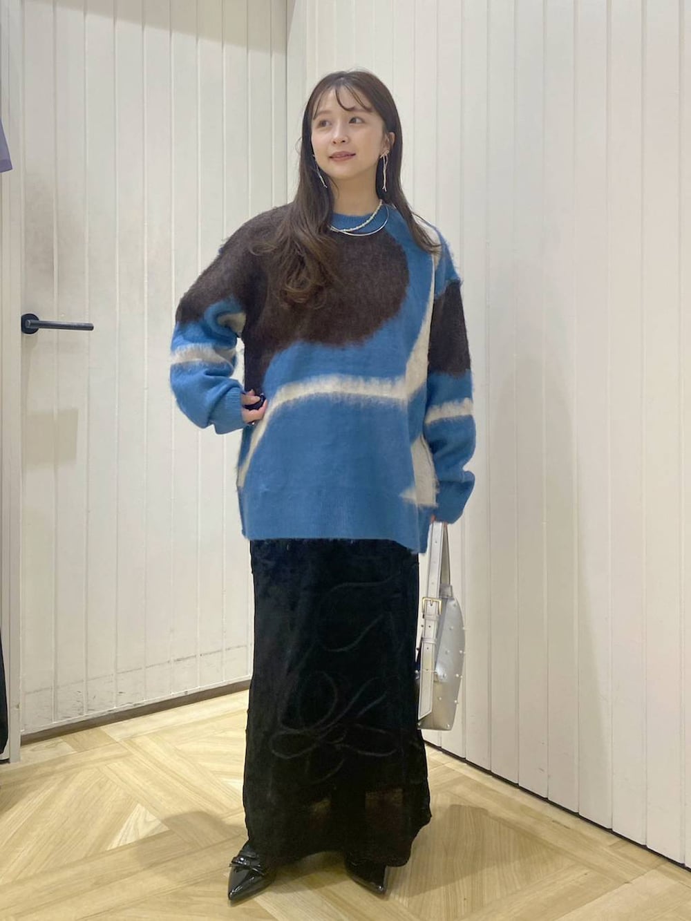 ブラック系のパンプス、ブルー系のニット/セーター、ブラック系のスカートを着用したレディースの秋コーディネートの2枚目の写真