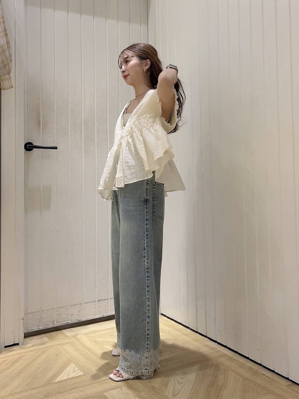 ゴールド系のタンクトップ、ブルー系のデニムパンツ、ホワイト系のサンダルを着用したレディースの夏コーディネートの2枚目の写真