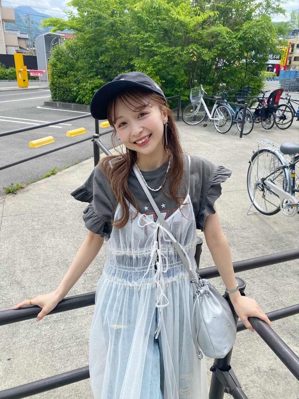 シルバー系のショルダーバッグ、シルバー系のサンダル、ベージュ系のワンピースを着用したレディースの春コーディネートの2枚目の写真