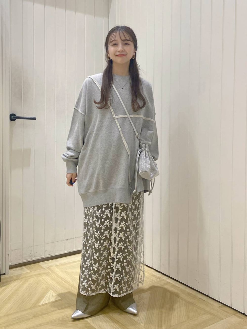 ブラウン系のスラックス、ホワイト系のスカート、シルバー系のショルダーバッグを着用したレディースの秋コーディネートの3枚目の写真