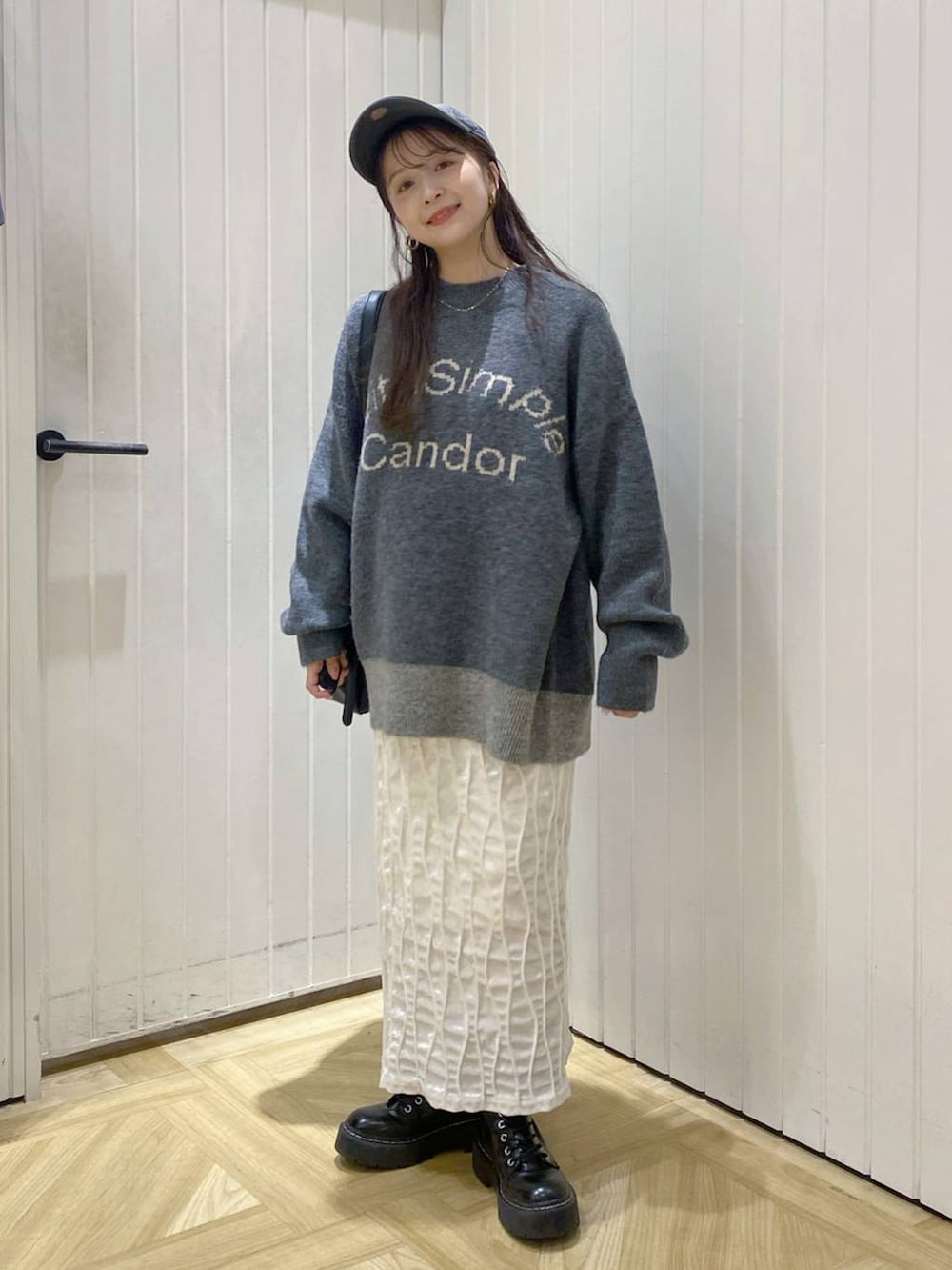 グレー系のニット/セーター、ホワイト系のスカート、ブラック系のショルダーバッグを着用したレディースの秋コーディネートの2枚目の写真