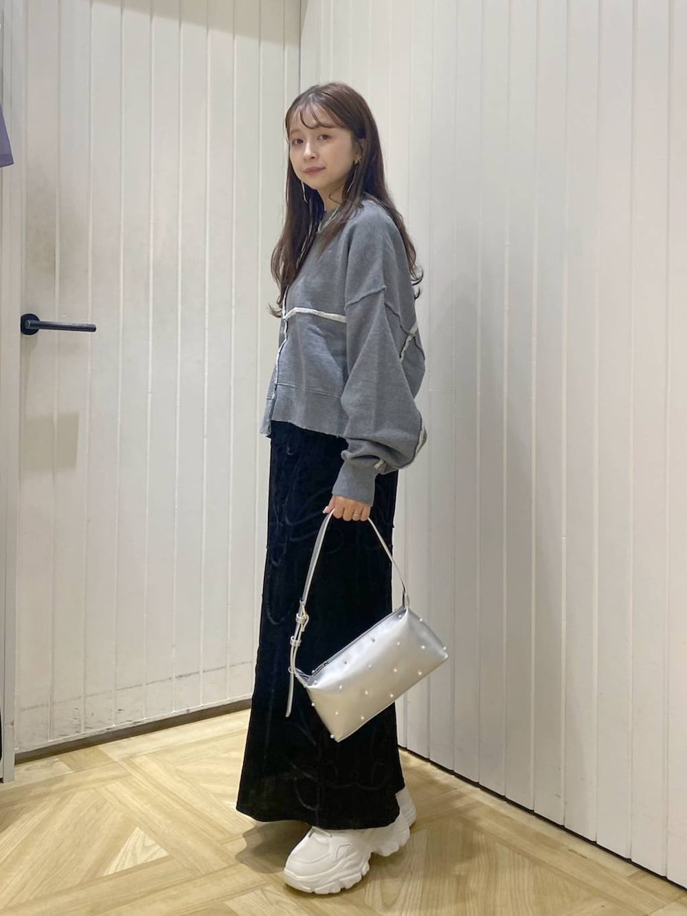 グレー系のスウェット、ブラック系のスカート、ホワイト系のスニーカーを着用したレディースの秋コーディネートの2枚目の写真
