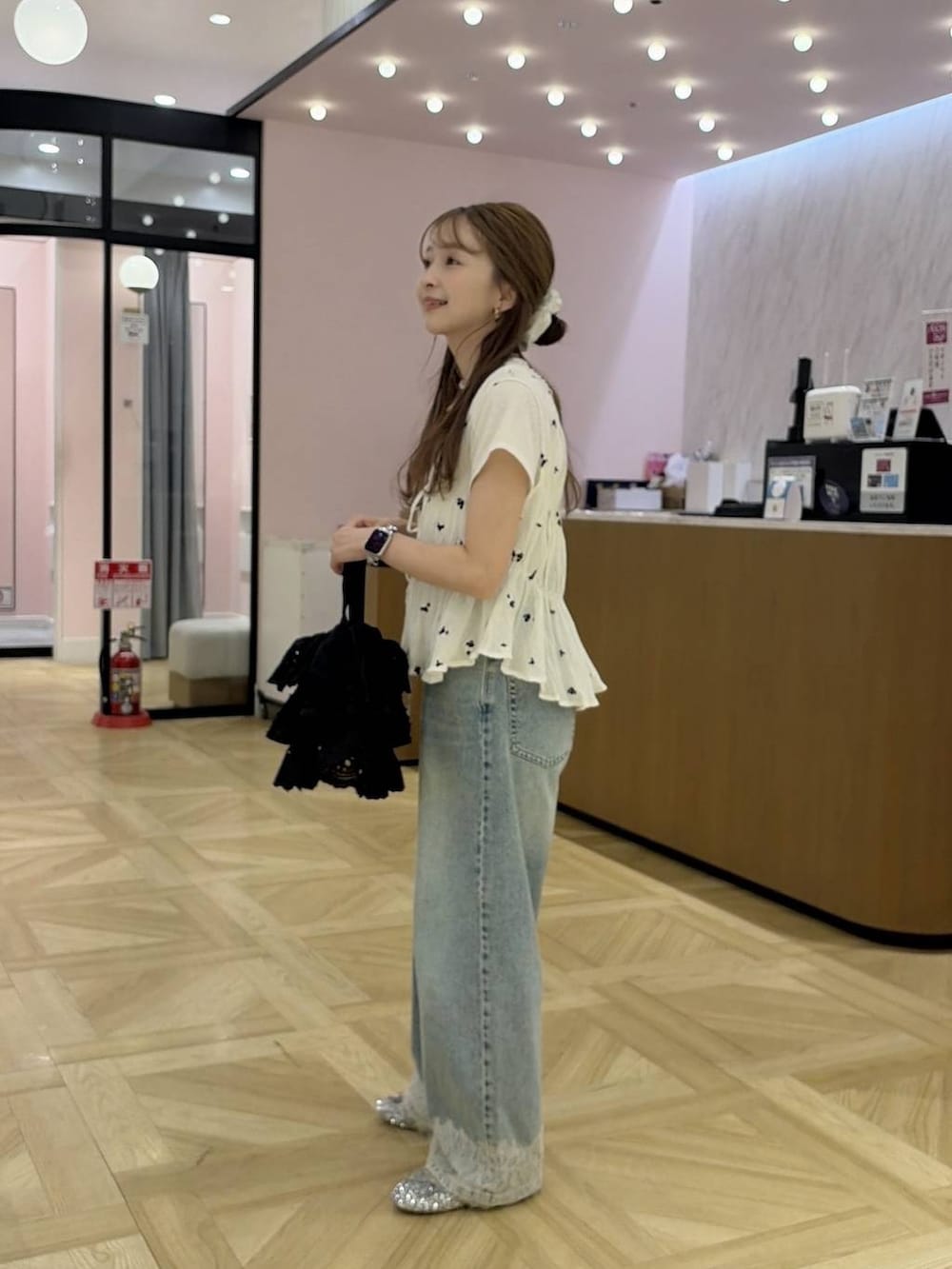 ブルー系のデニムパンツ、ブラック系のハンドバッグ、ホワイト系のシャツ/ブラウスを着用したレディースの夏コーディネートの2枚目の写真