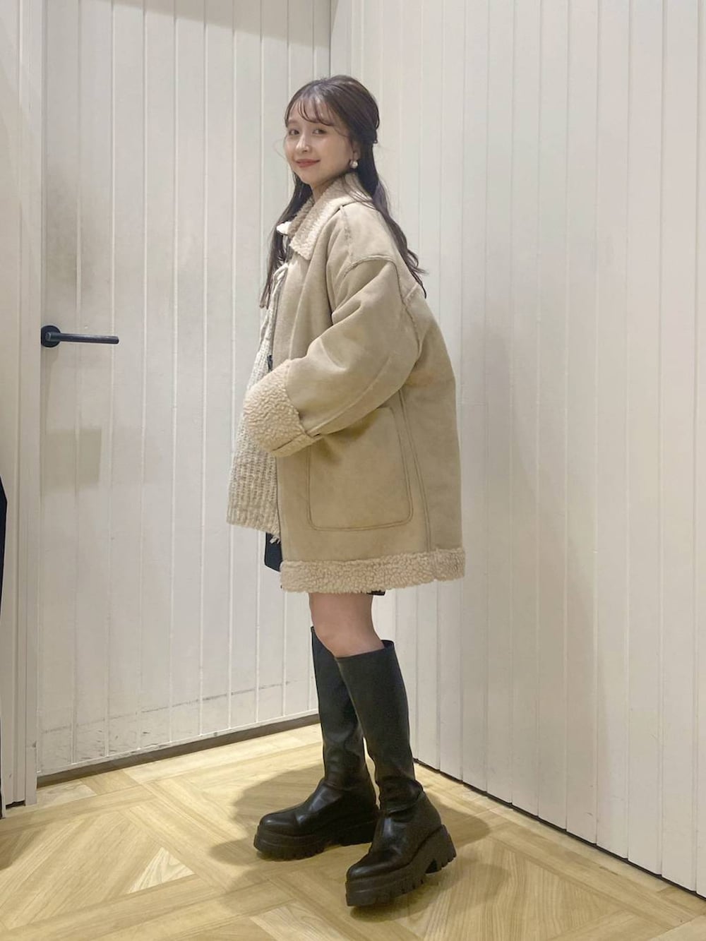 ホワイト系のニット/セーター、ブラウン系のショルダーバッグ、ブラック系のブーツを着用したレディースの秋コーディネートの2枚目の写真