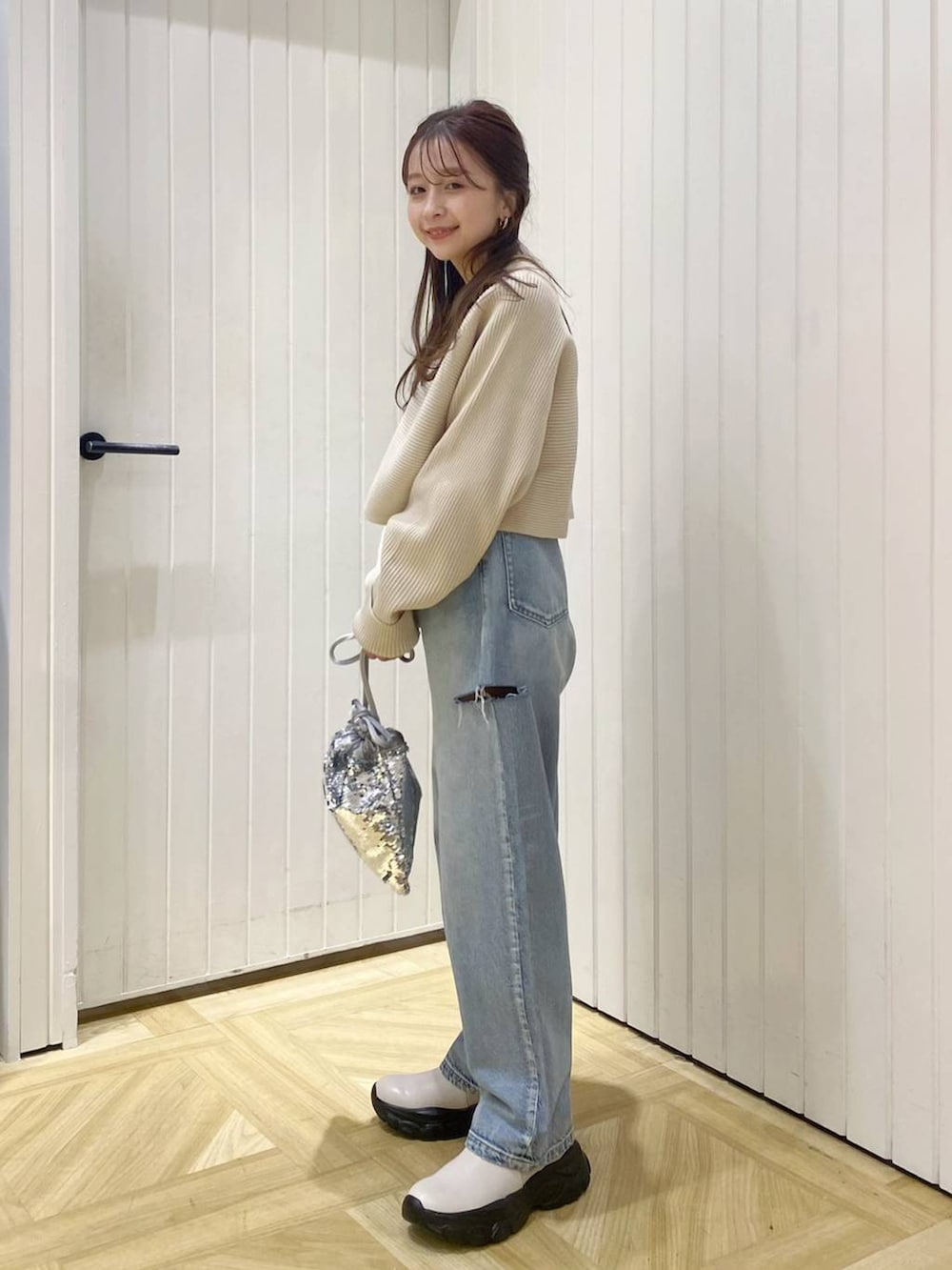 ブルー系のデニムパンツ、シルバー系のハンドバッグ、ホワイト系のブーツを着用したレディースの冬コーディネートの3枚目の写真