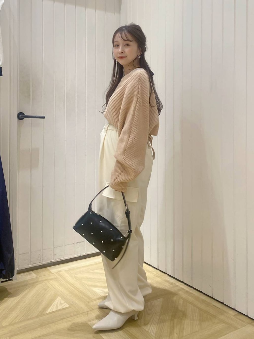 ピンク系のニット/セーター、ホワイト系のスラックス、ホワイト系のブーツを着用したレディースの秋コーディネートの2枚目の写真