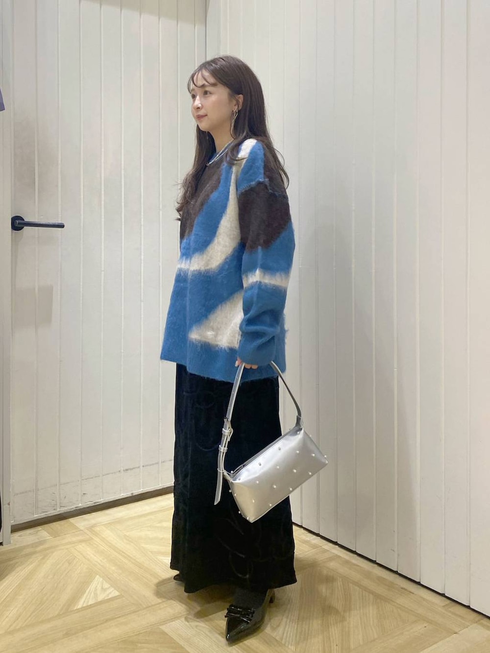 ブラック系のパンプス、ブルー系のニット/セーター、ブラック系のスカートを着用したレディースの秋コーディネートの3枚目の写真