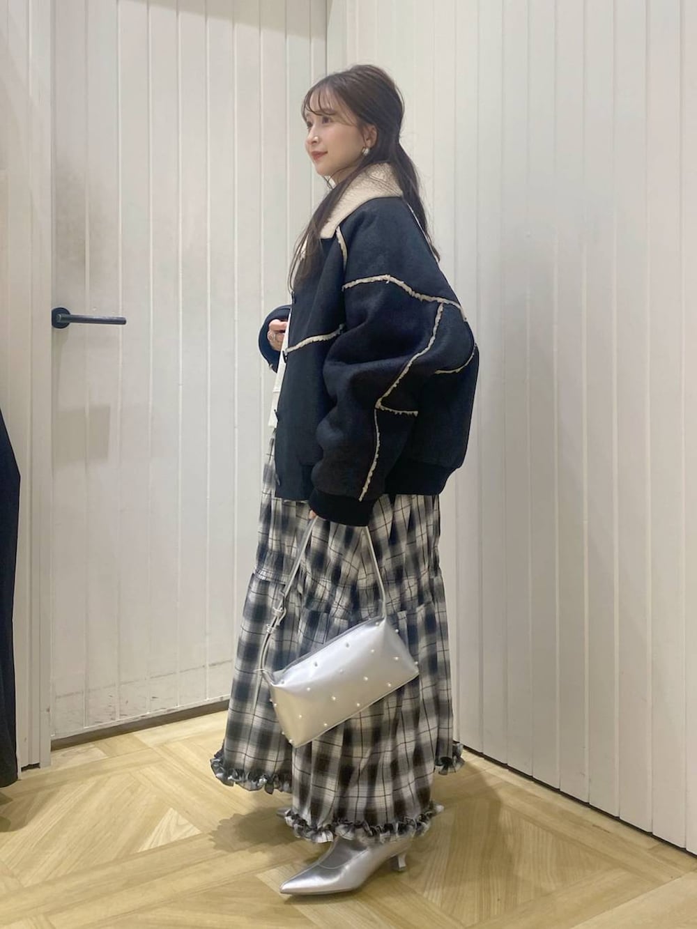 ブラック系のスカート、ブラック系のブルゾン、シルバー系のブーツを着用したレディースの秋コーディネートの2枚目の写真