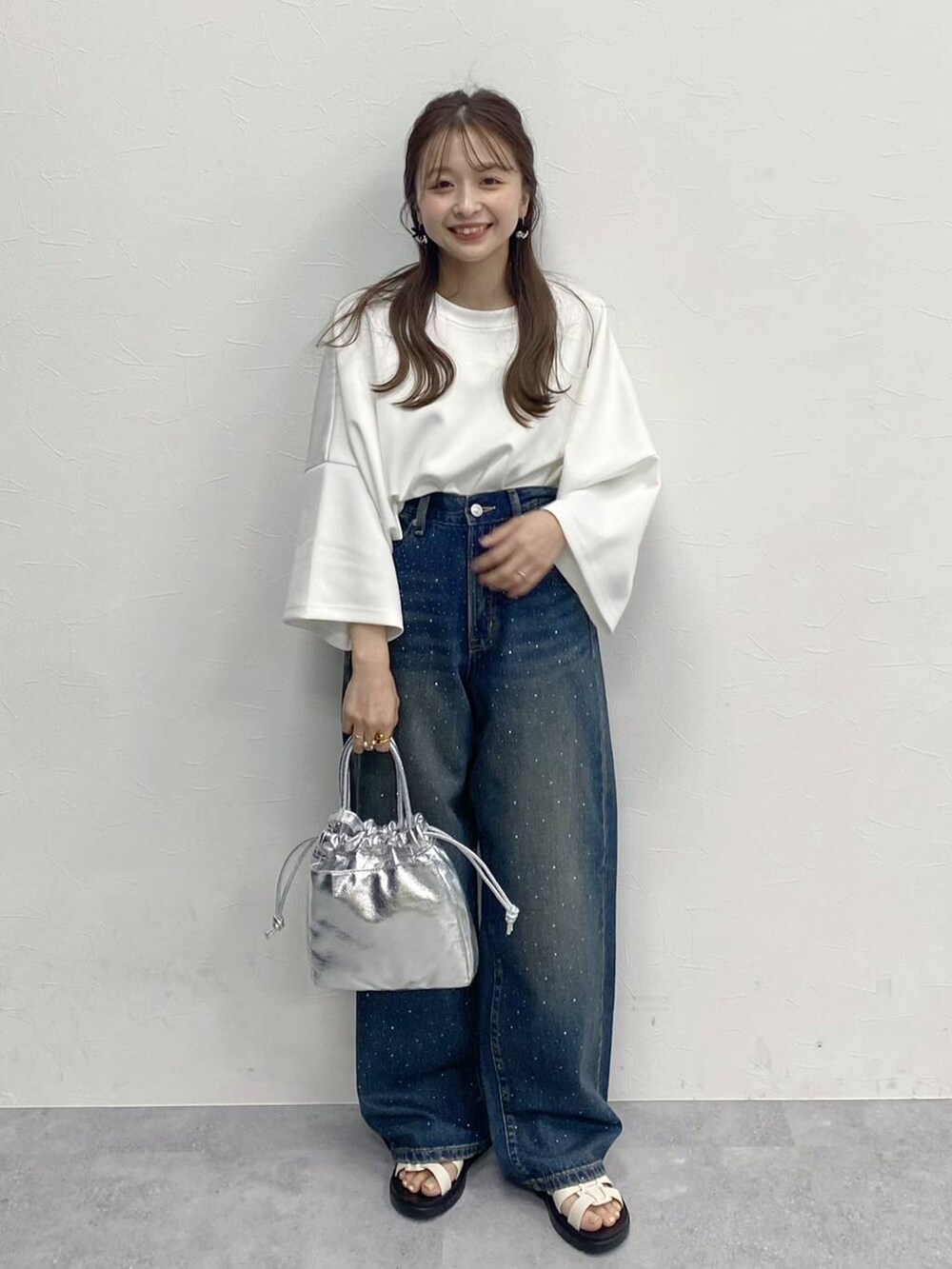 ブルー系のデニムパンツ、ホワイト系のスニーカー、シルバー系のハンドバッグを着用したレディースの春コーディネートの2枚目の写真