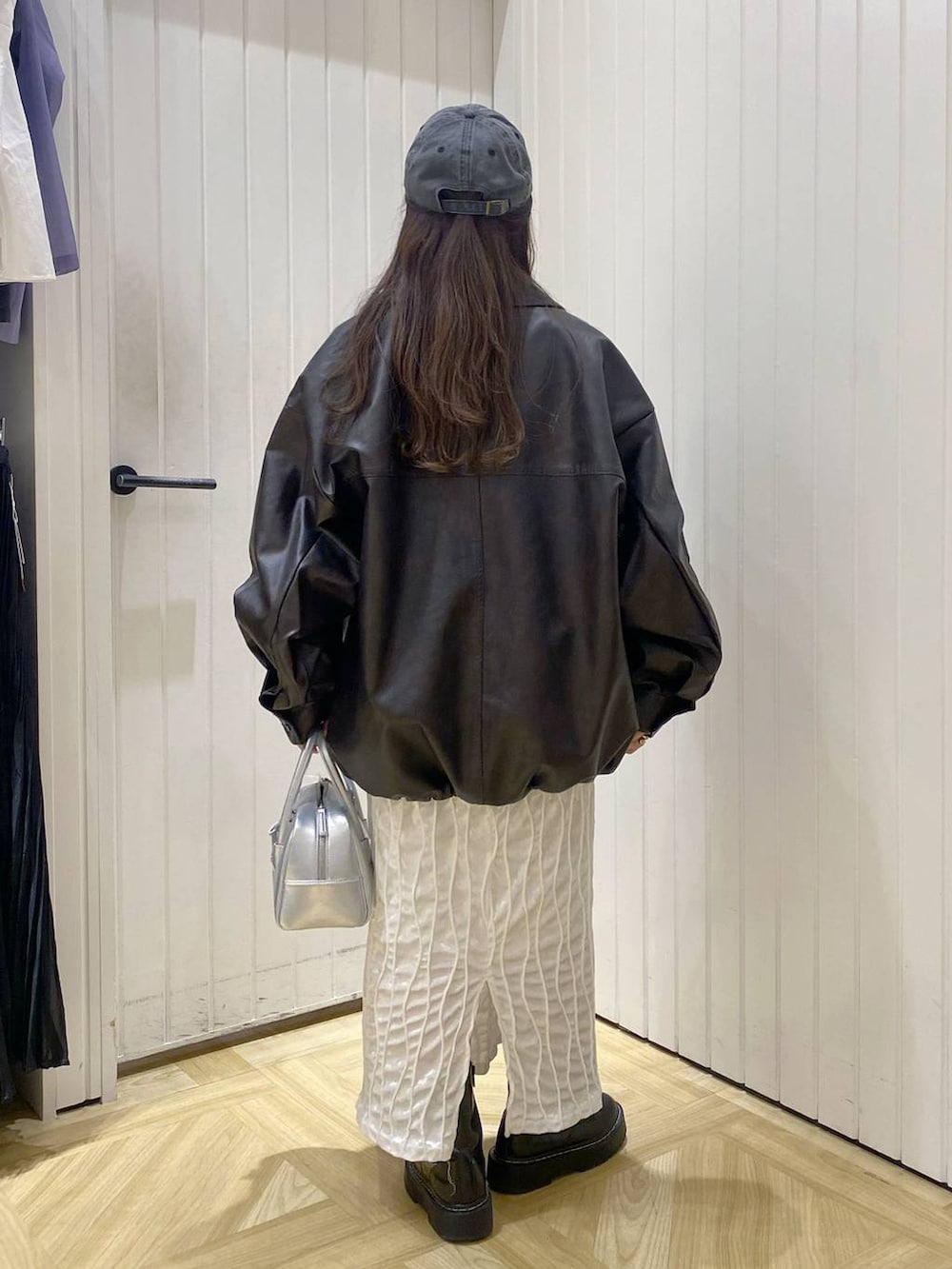 ブラウン系のブルゾン、シルバー系のボストンバッグ、グレー系のニット/セーターを着用したレディースの秋コーディネートの3枚目の写真