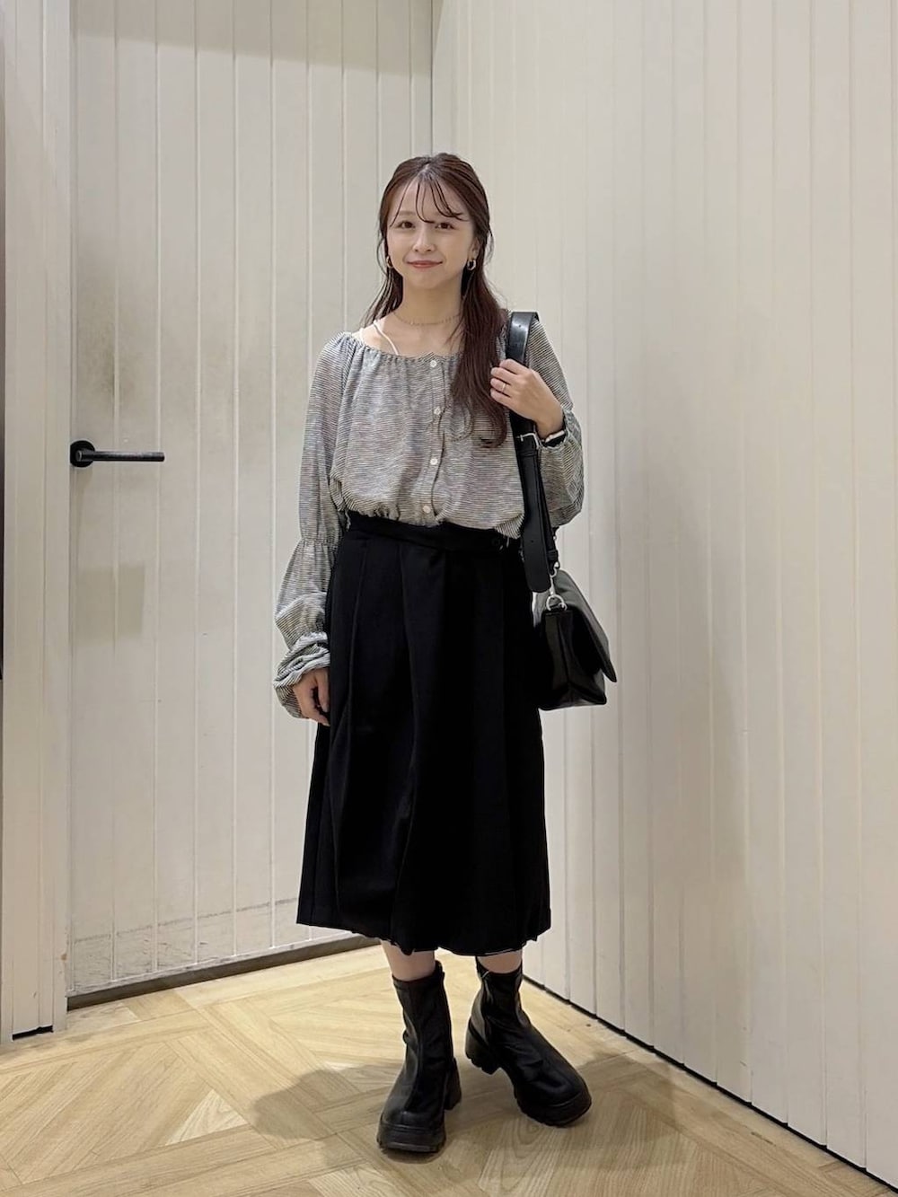 ブラック系のブーツ、ブラック系のショルダーバッグ、ブラック系のTシャツ/カットソーを着用したレディースの秋コーディネートの3枚目の写真