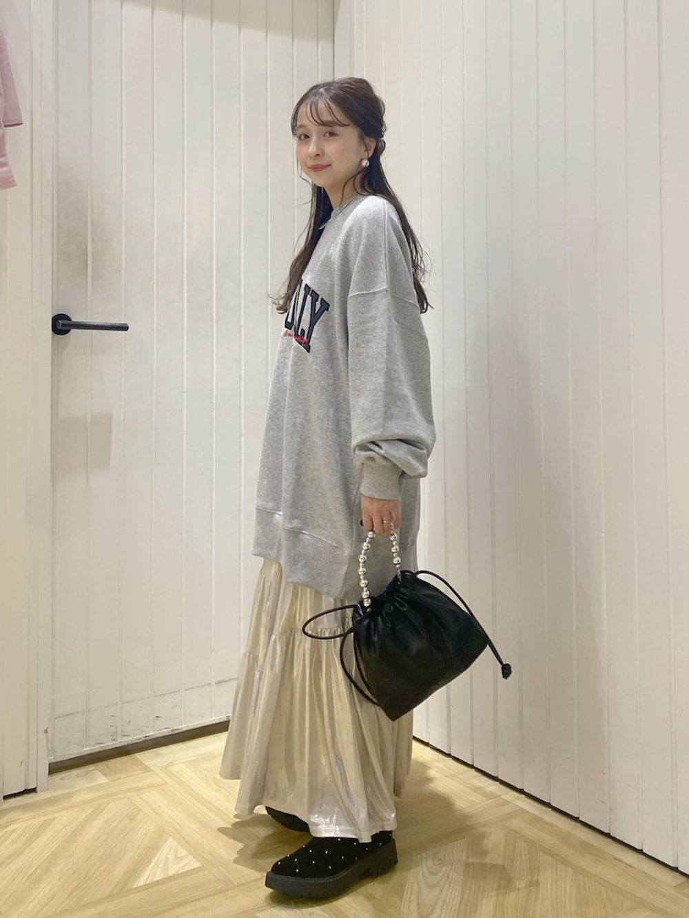 グレー系のスウェット、ホワイト系のスカート、ブラック系のショルダーバッグを着用したレディースの秋コーディネートの2枚目の写真