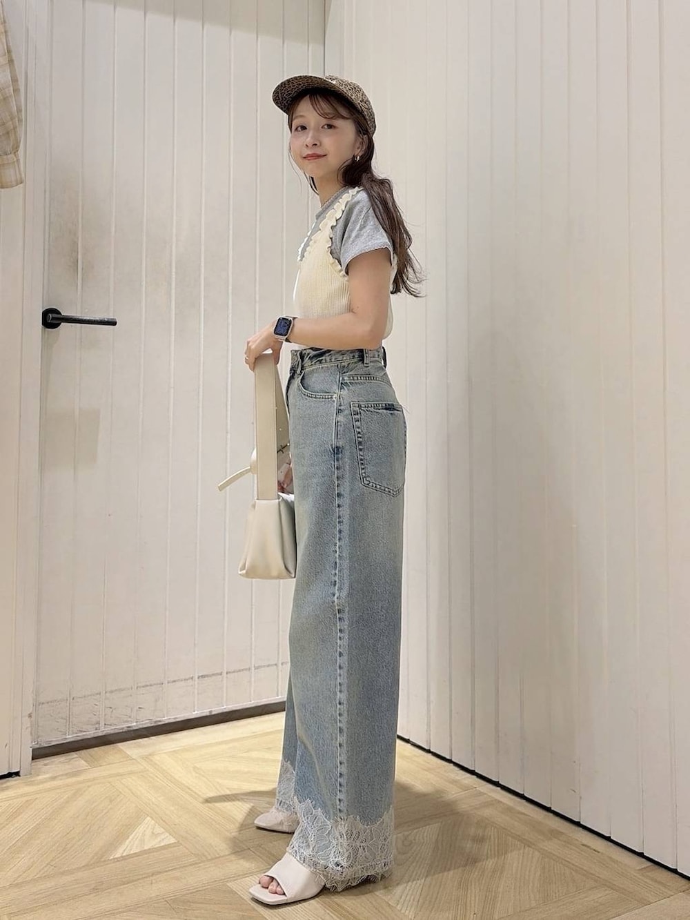 ブルー系のデニムパンツ、ホワイト系のタンクトップ、ホワイト系のショルダーバッグを着用したレディースの春コーディネートの2枚目の写真